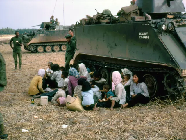 In this image there are group of people sitting in the middle of the image. There are military...