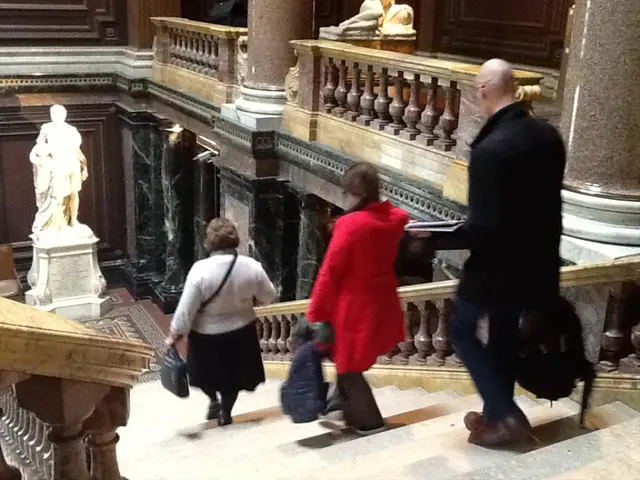 In this age we can see three persons walking on steps. They are holding bags. On the sides of the...